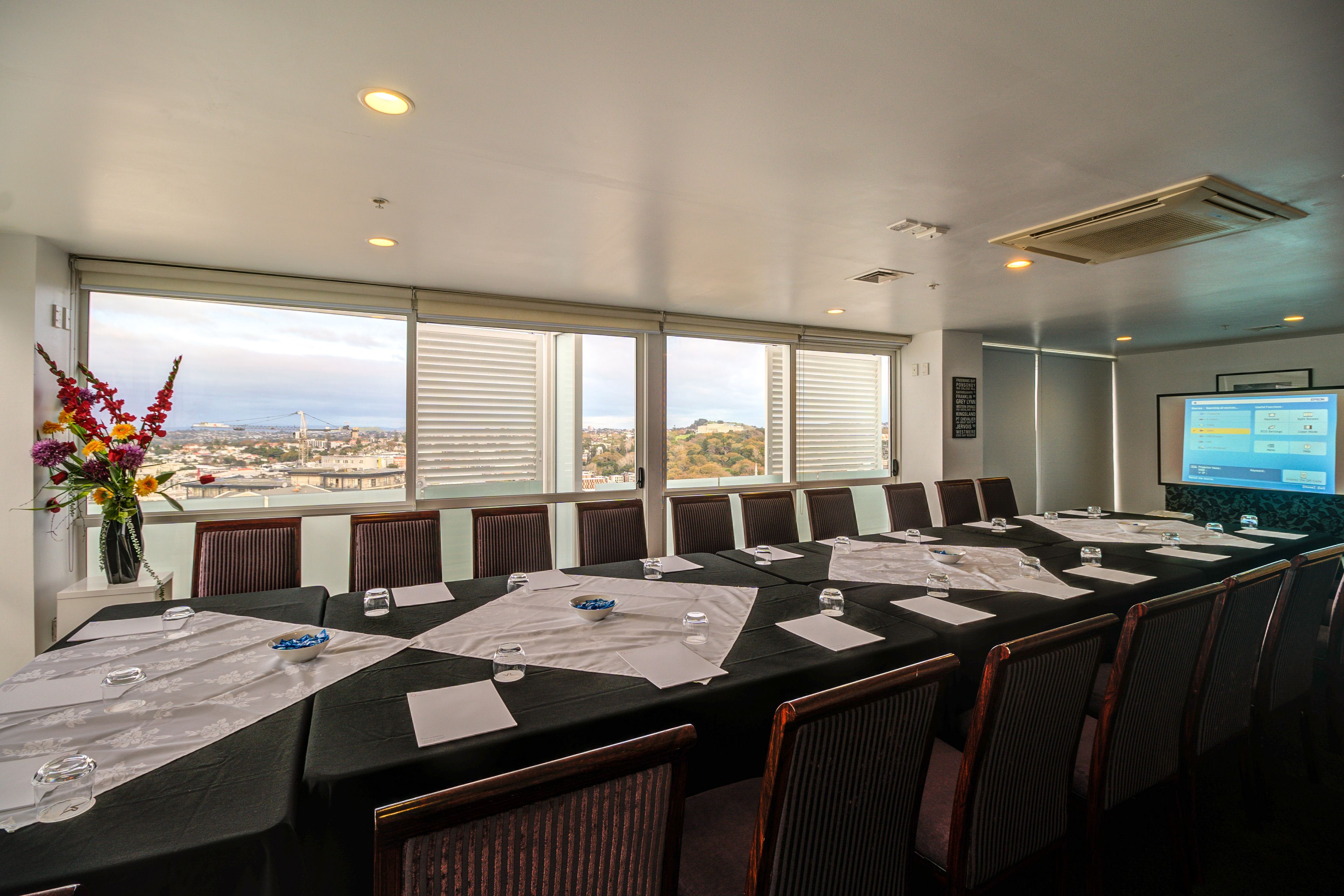 A conference room with a long table, chairs, and a projector screen.