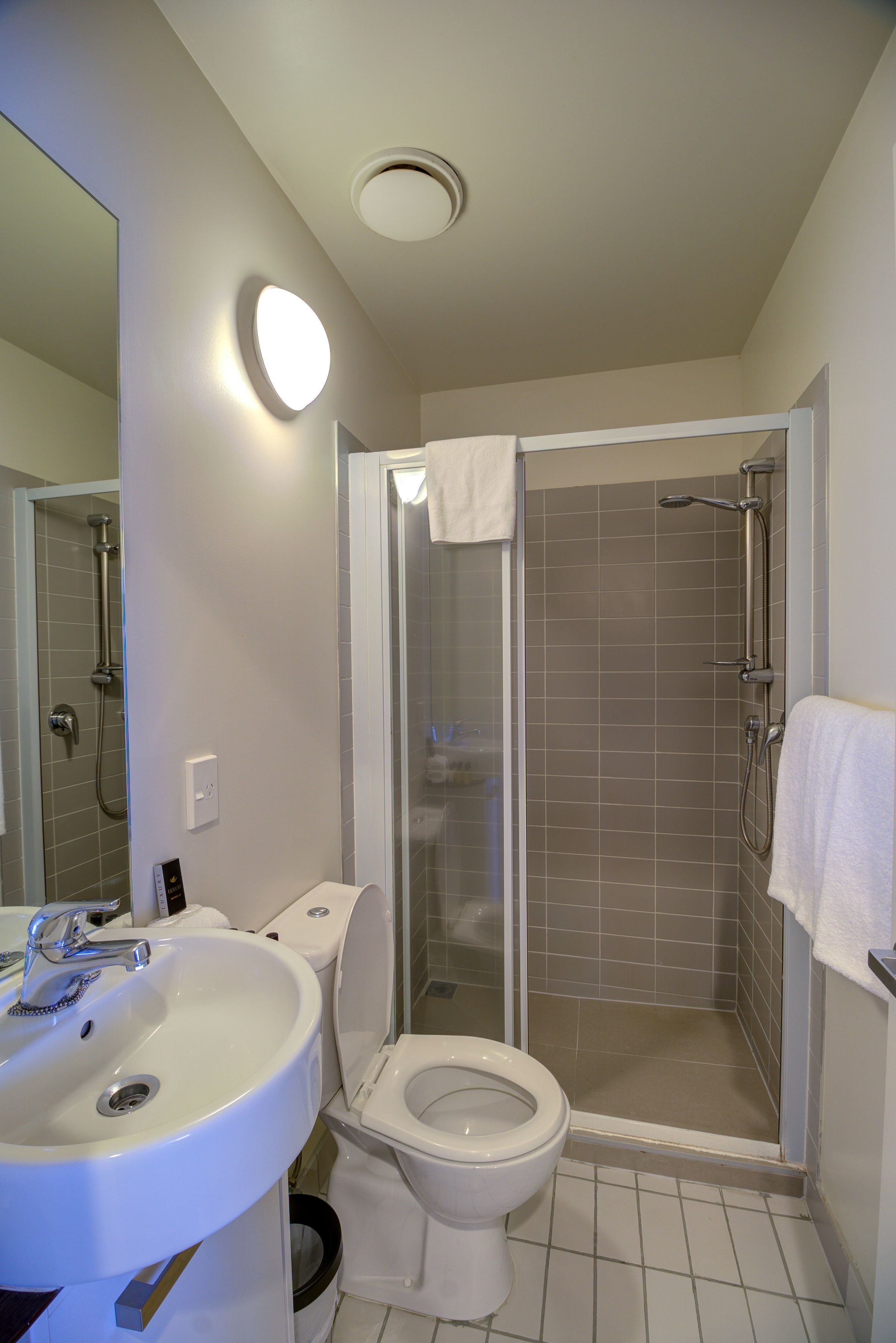 A bathroom with a sink, toilet, and a glass-enclosed shower area.