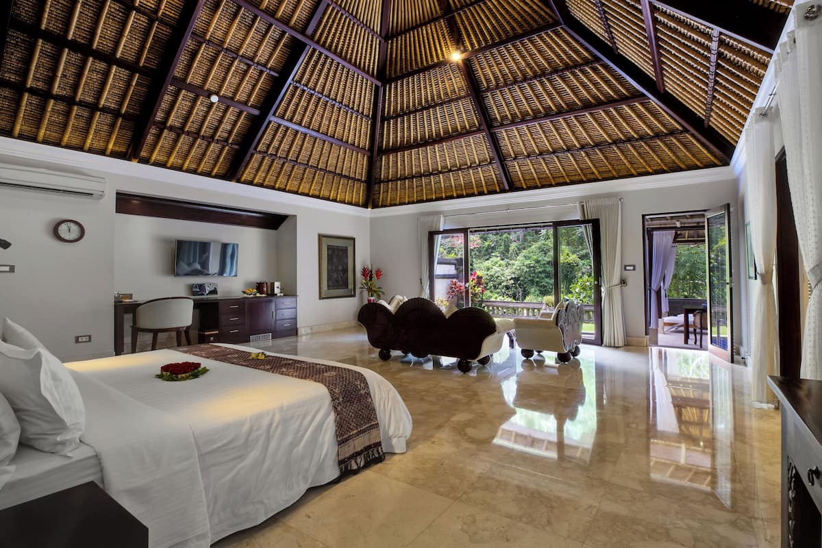 A spacious room with a large bed, a desk, and a view of the outdoors.