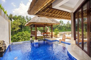 A pool area with a thatched-roof gazebo, lounge chairs, and a view of lush greenery. - Viceroy Bali (Ubud)