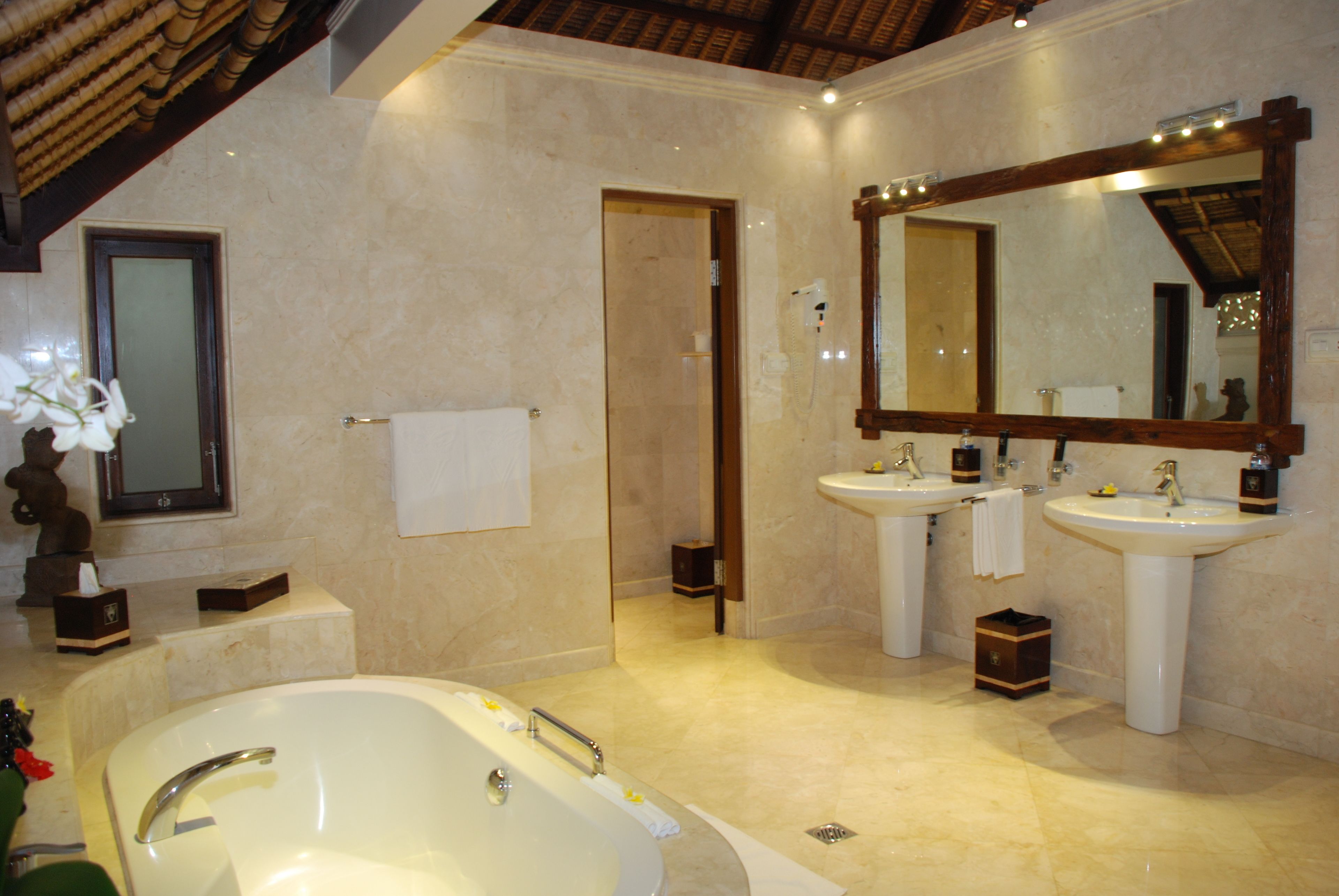 A spacious bathroom with a large bathtub, two sinks, and a mirror.
