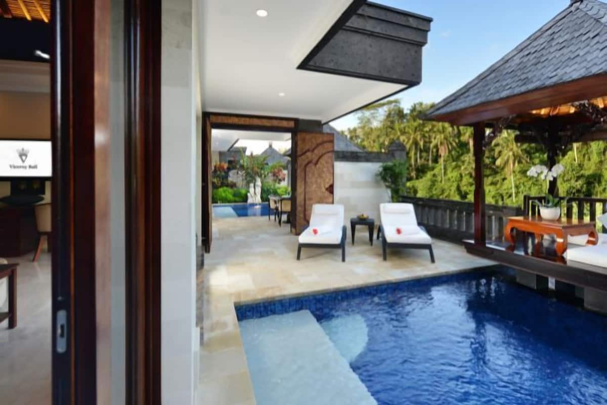 A pool area with lounge chairs, a wooden deck, and a view of the surrounding landscape.