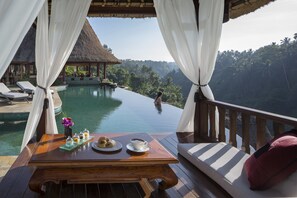 A wooden deck with a table set for breakfast, overlooking a pool and lush greenery. - Viceroy Bali (Ubud)