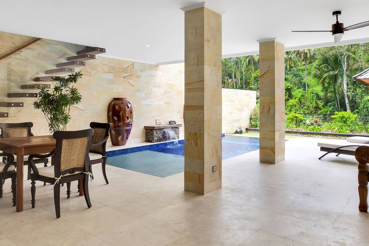 A spacious indoor area with a pool, a dining set, and a seating area with a view of the outdoors.