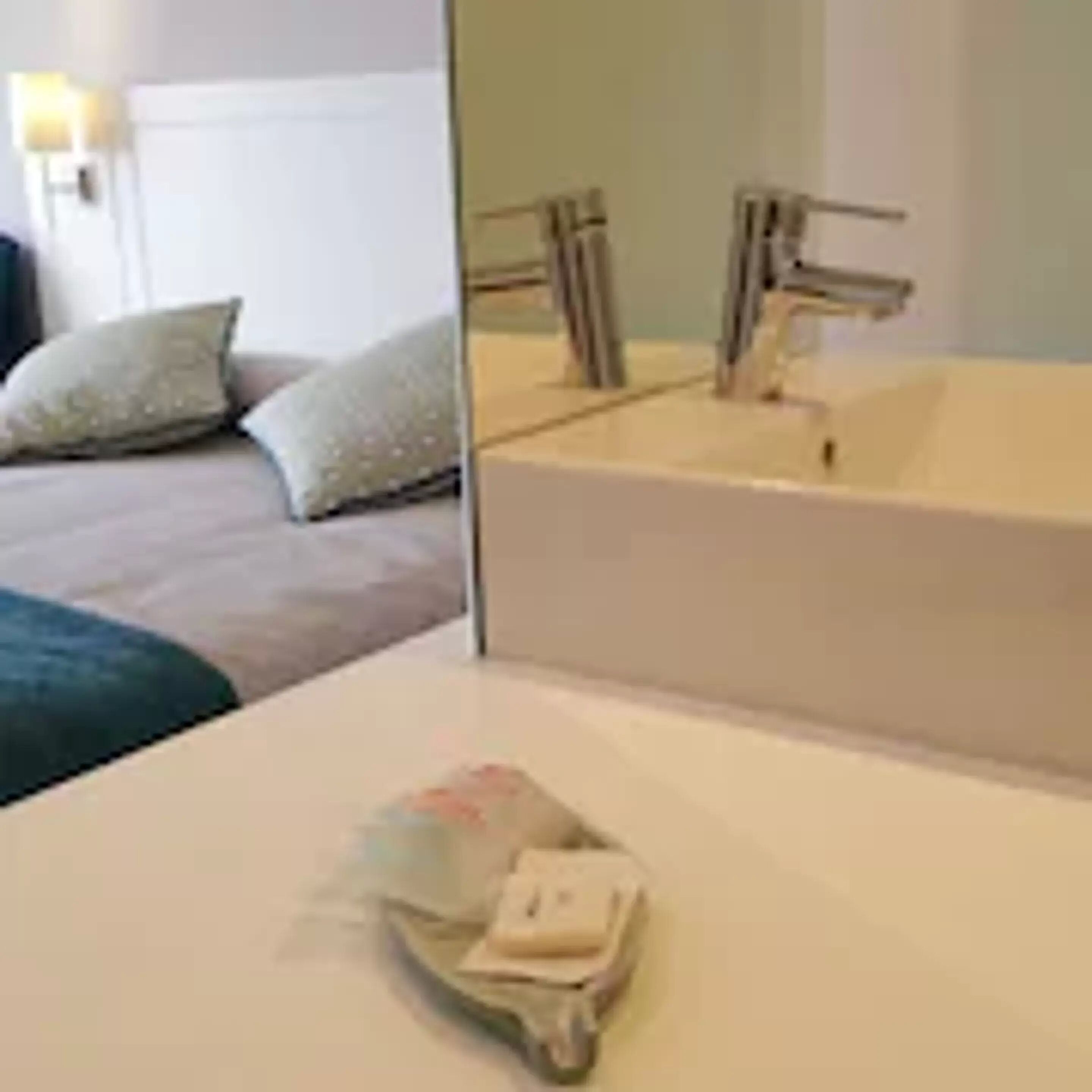 Una habitación de hotel con una cama grande, un baño con bañera y un espejo.