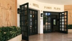 L’entr ée d’un hôtel avec des portes en verre, une enseigne indiquant « HÔTEL PINOS PLAYA » et un sol carrelé.