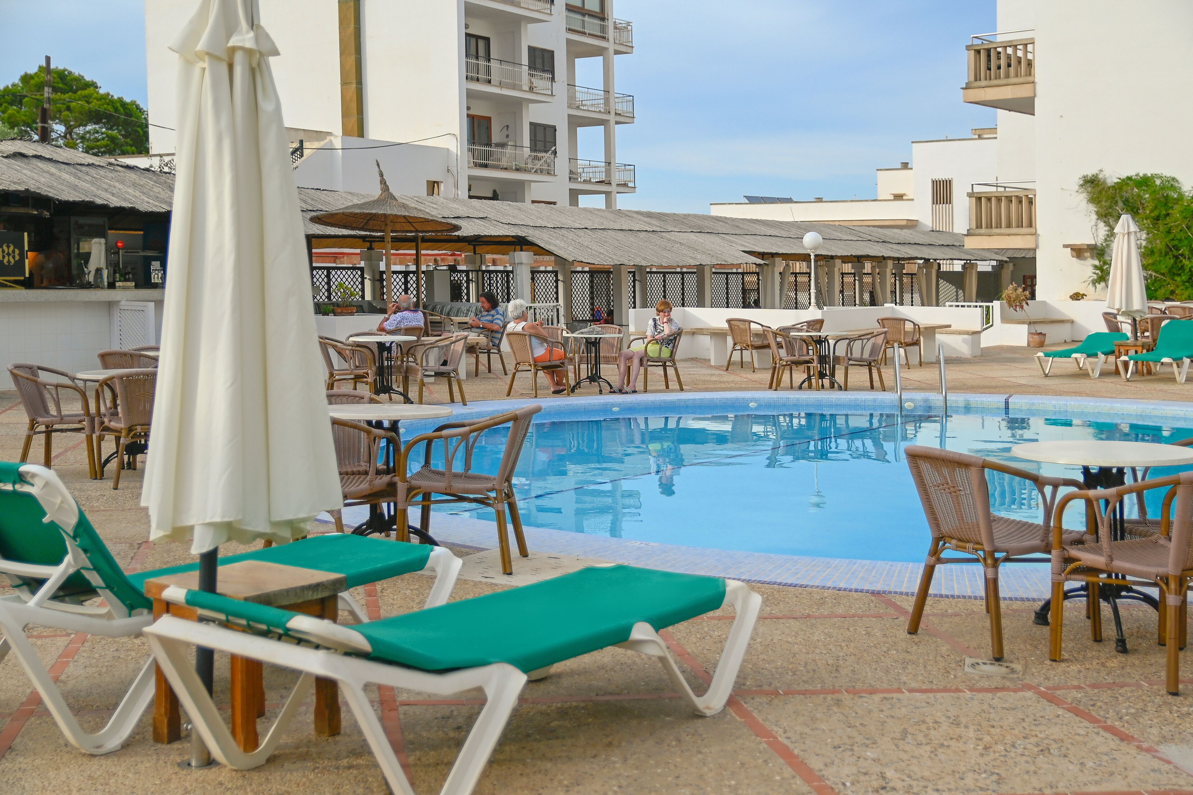 Ein Poolbereich mit Liegestühlen, Tischen und Sonnenschirmen.