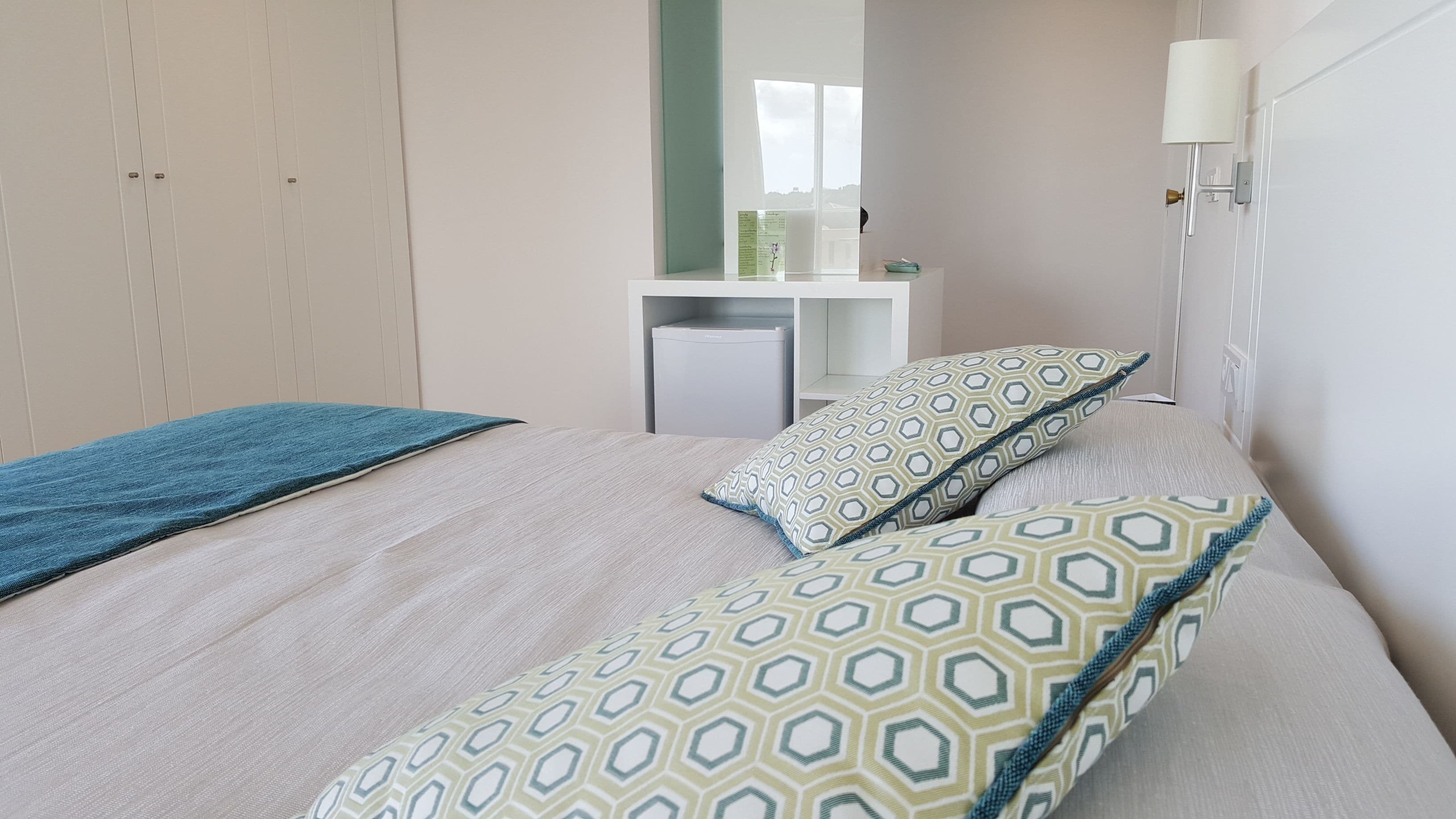 A bedroom with a bed, a bedside table, a lamp, and a wardrobe.