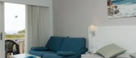 Ein Hotelzimmer mit einem Bett, einem blauen Sofa, einem kleinen Tisch und einem Fenster mit Vorhängen.