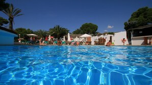 Une piscine à l’eau d’un bleu limpide, entourée de chaises longues et de parasols.