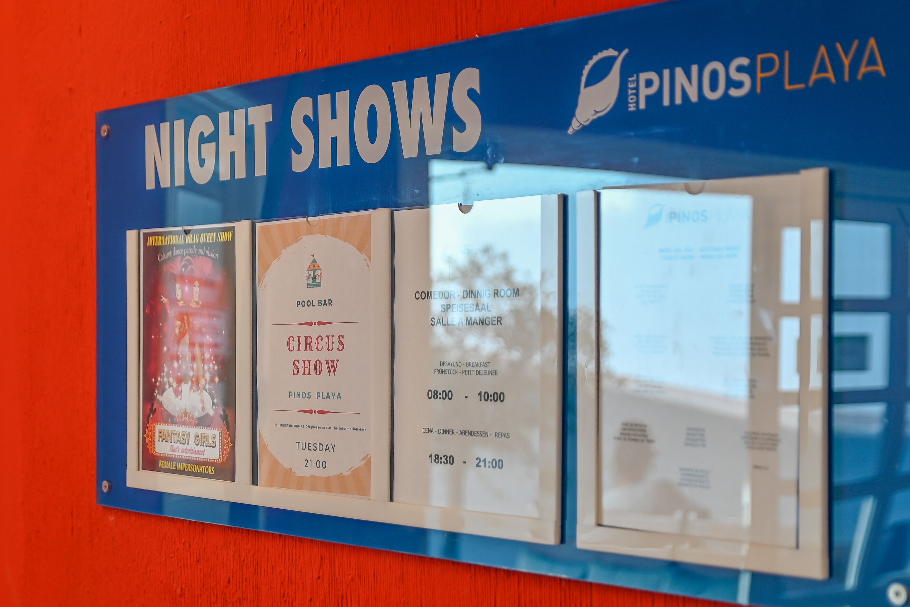 Une affiche indiquant les spectacles nocturnes proposés à l’hôtel Pinos Playa, notamment un spectacle de cirque et une performance d’une artiste se produisant en travesti.