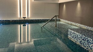An indoor swimming pool with a tiled floor and walls, a metal handrail, and vertical light fixtures. - Kenton Palace Bariloche (San Carlos de Bariloche)