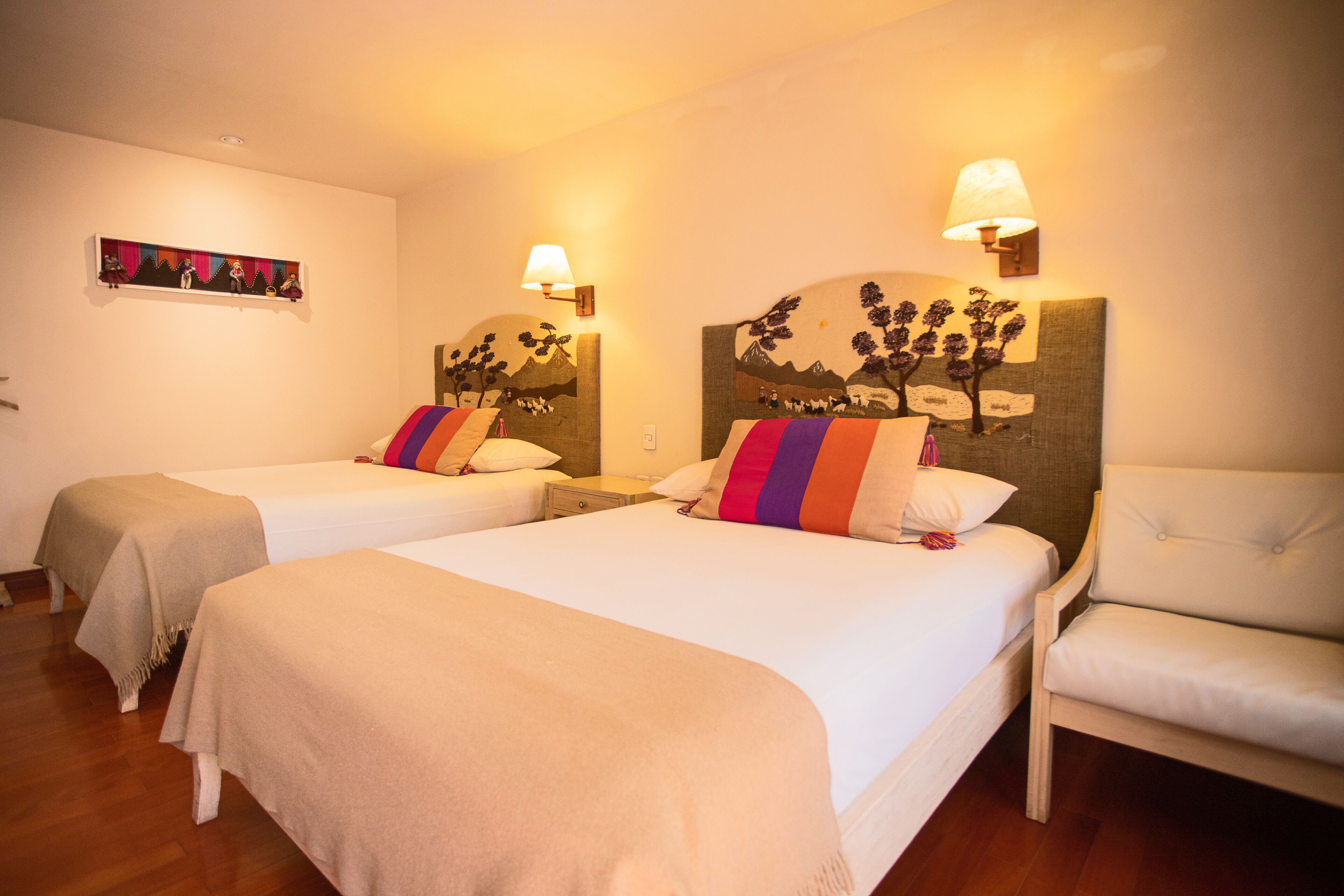 Habitación de hotel con dos camas individuales, una silla y un cuadro en la pared.