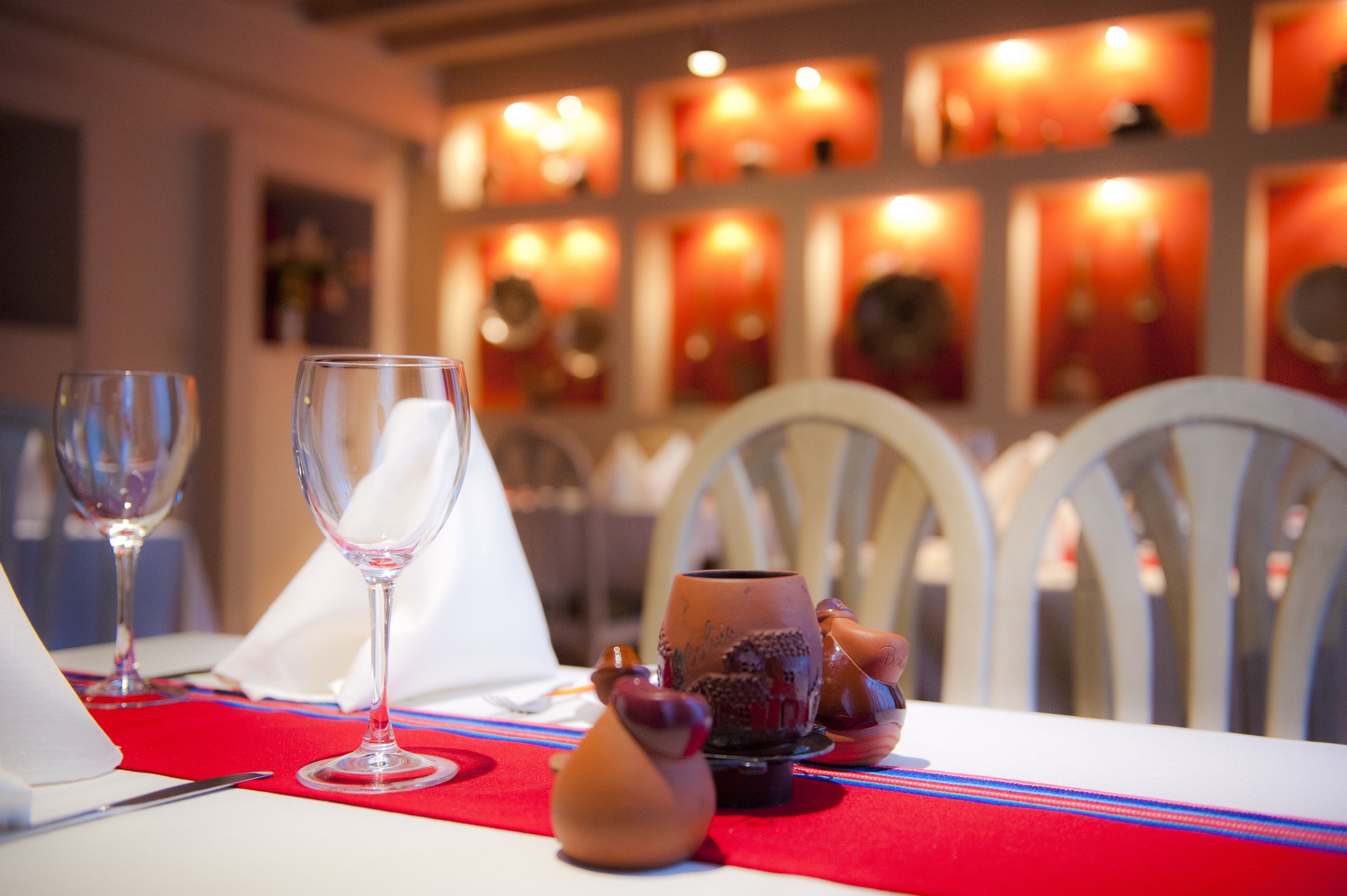 Uma mesa de jantar posta com taças de vinho, guardanapo e objetos decorativos.