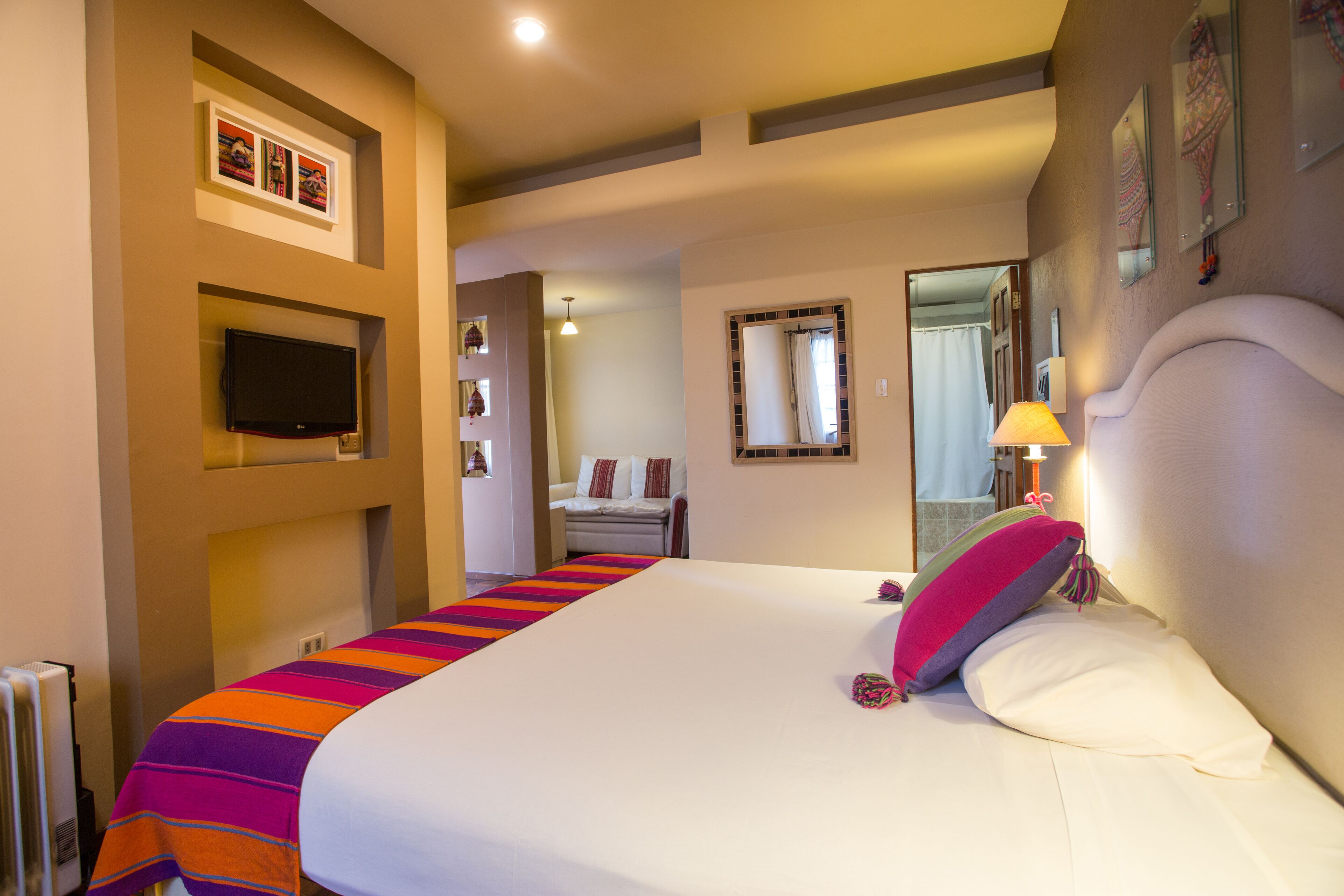 Habitación de hotel con una cama grande, un televisor de pantalla plana, una mesita de noche y una ventana con cortinas.
