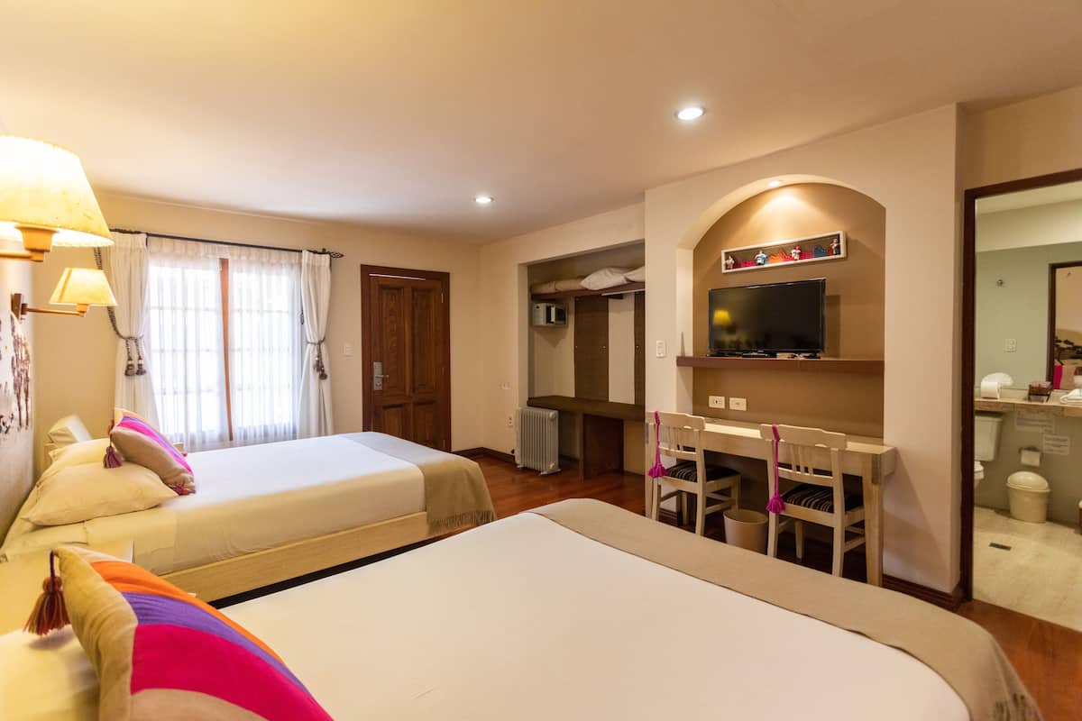A hotel room with two beds, a desk, a chair, a television, and a mirror.