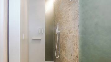Un baño moderno con ducha, paredes de azulejos y un estante pequeño.
