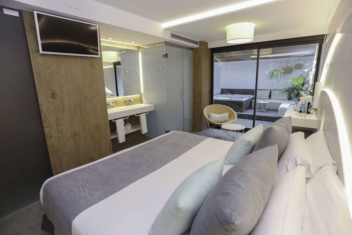 Une chambre d’hôtel moderne, équipée d’un lit, d’une salle de bain avec un lavabo, d’une chaise et offrant une vue sur l’extérieur.
