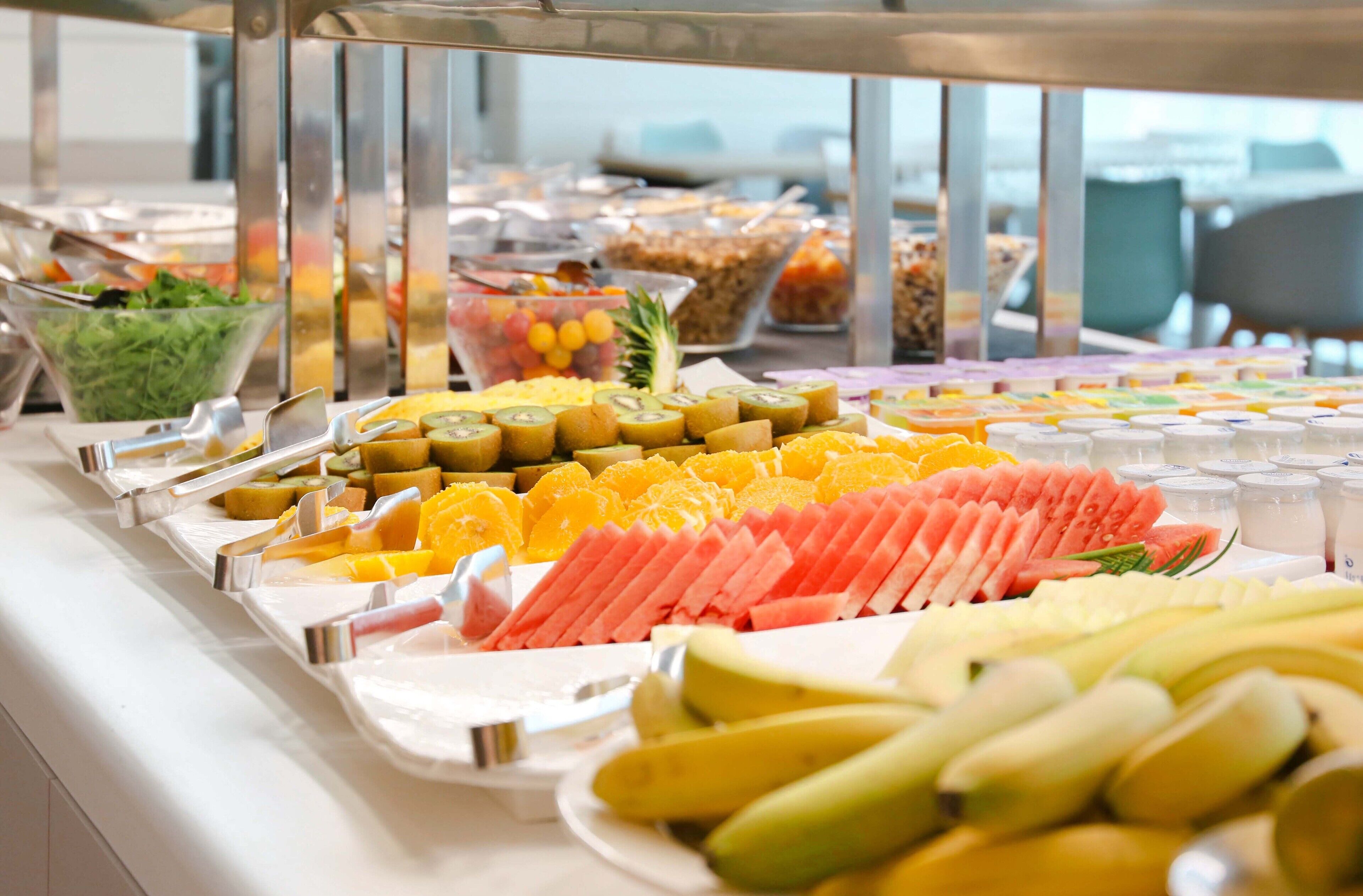 Un buffet proposant une variété de fruits et de légumes, notamment des bananes, des pastèques et des kiwis.