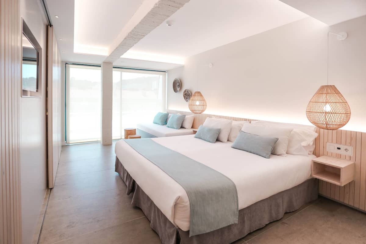 Une chambre moderne avec un grand lit, des tables de chevet et une vue sur l’extérieur.