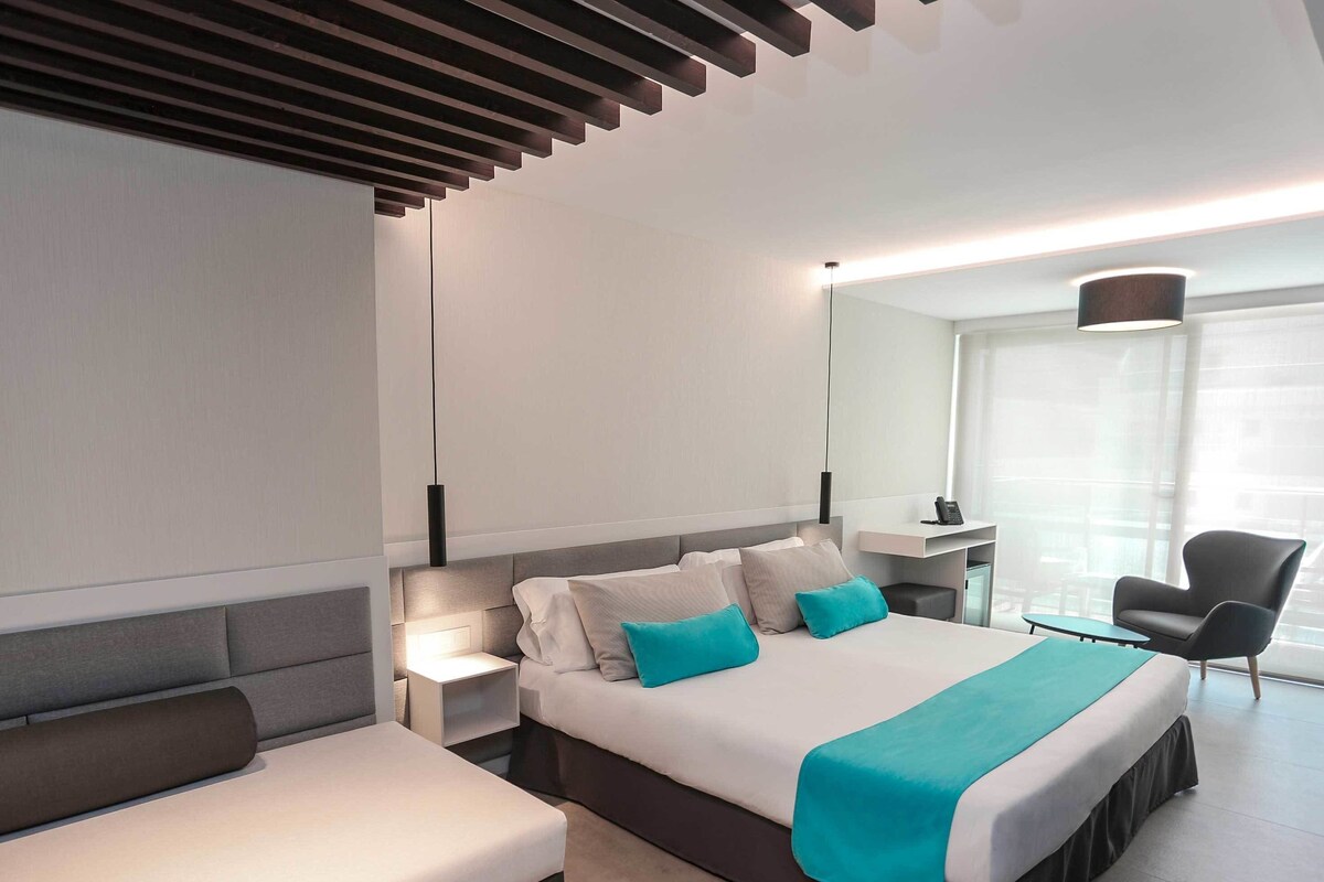 Una habitación de hotel moderna con cama, zona de estar, escritorio y una silla.