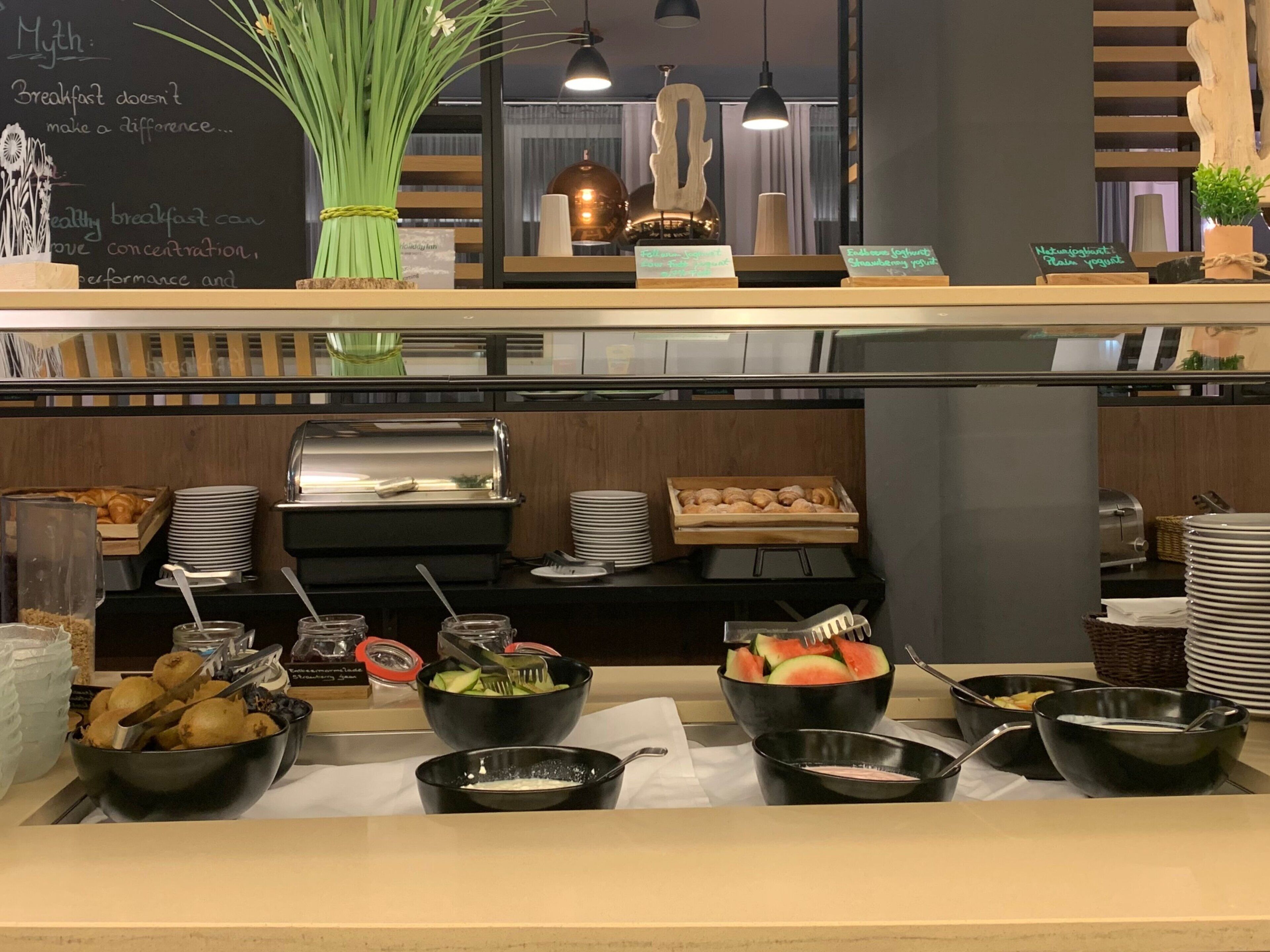 A breakfast buffet with various food options, including fruits, pastries, and condiments.