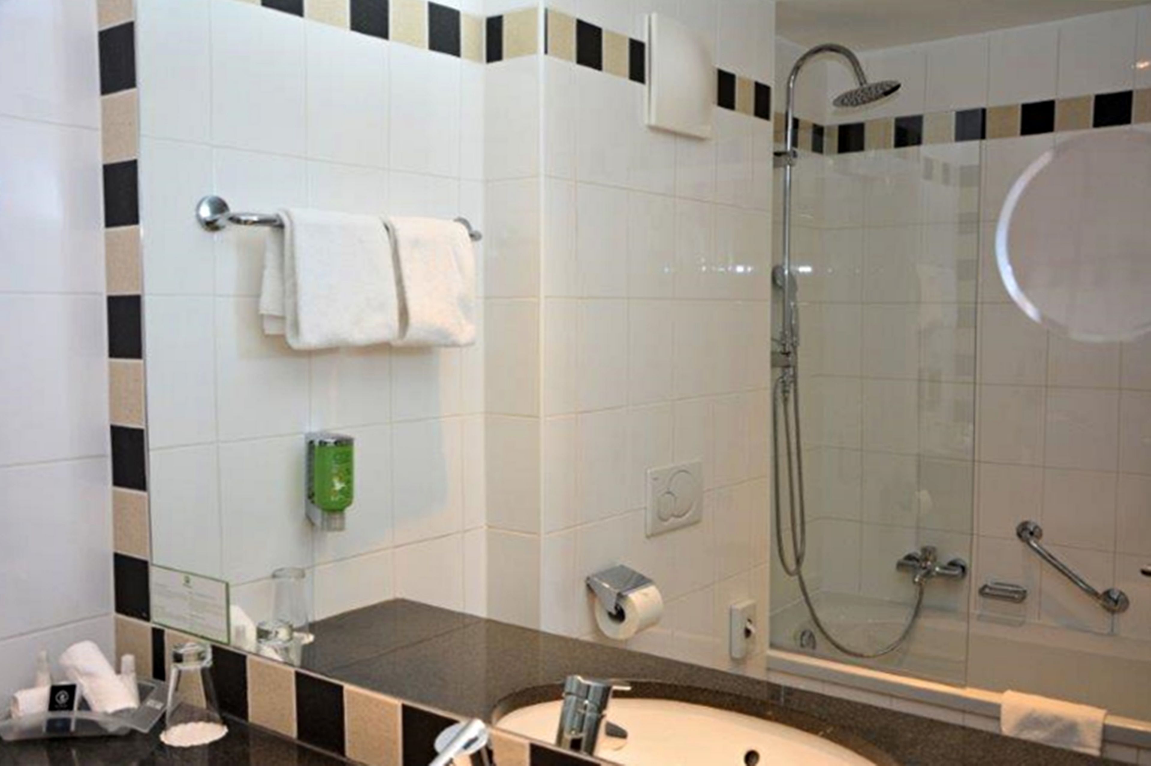 Een moderne badkamer met een douchecabine van glas, een wastafelmeubel en een handdoekhouder.