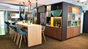 Un intérieur moderne avec un espace de restauration central, un bar et des étagères où sont exposés des livres et des objets décoratifs.