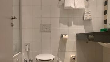 A modern bathroom with a toilet, bidet, and hand dryer. There are two white towels hanging on a towel rack.