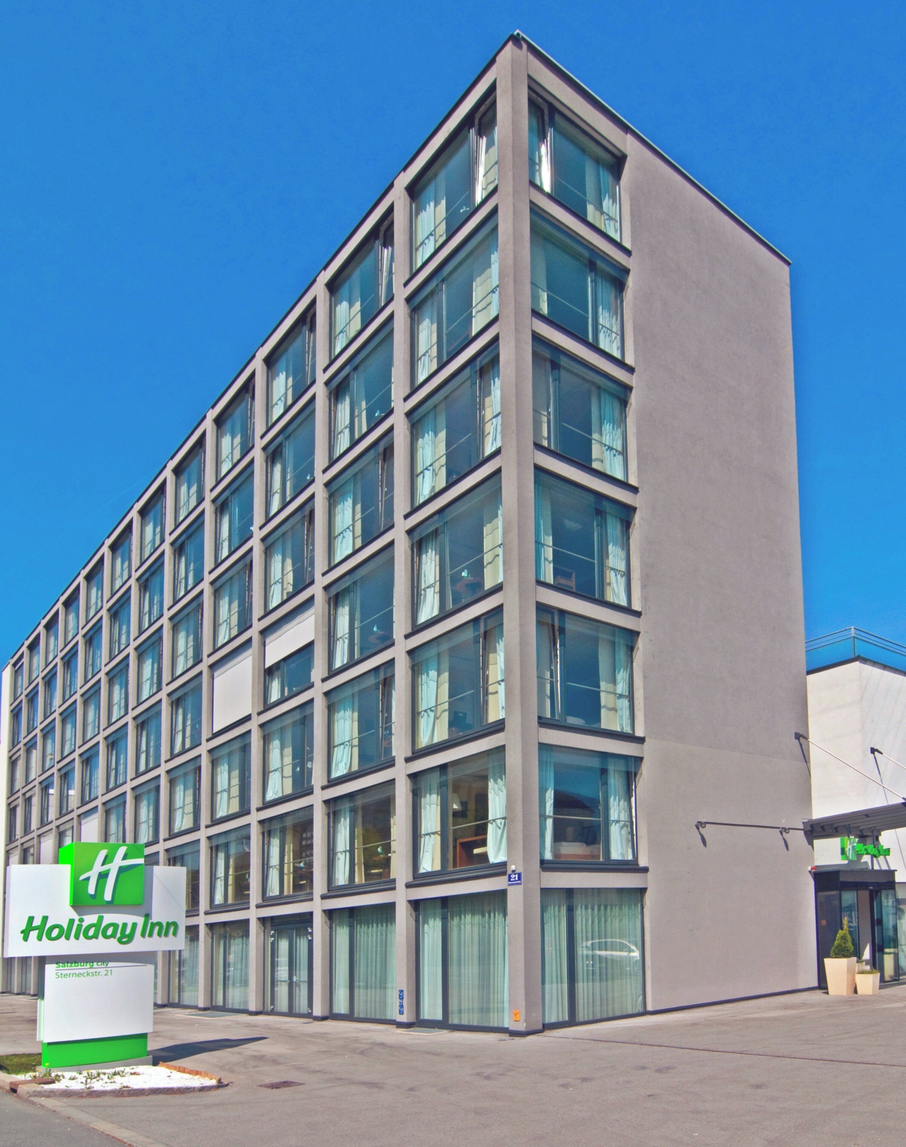 Un edificio moderno con varios pisos, grandes ventanales y un letrero de Holiday Inn.
