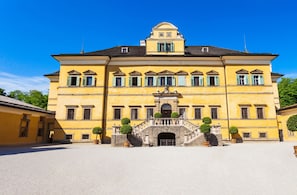 A large, yellow building with a symmetrical facade, multiple windows, and a central entrance with a staircase. - Holiday Inn Salzburg City by IHG (Salzburg)