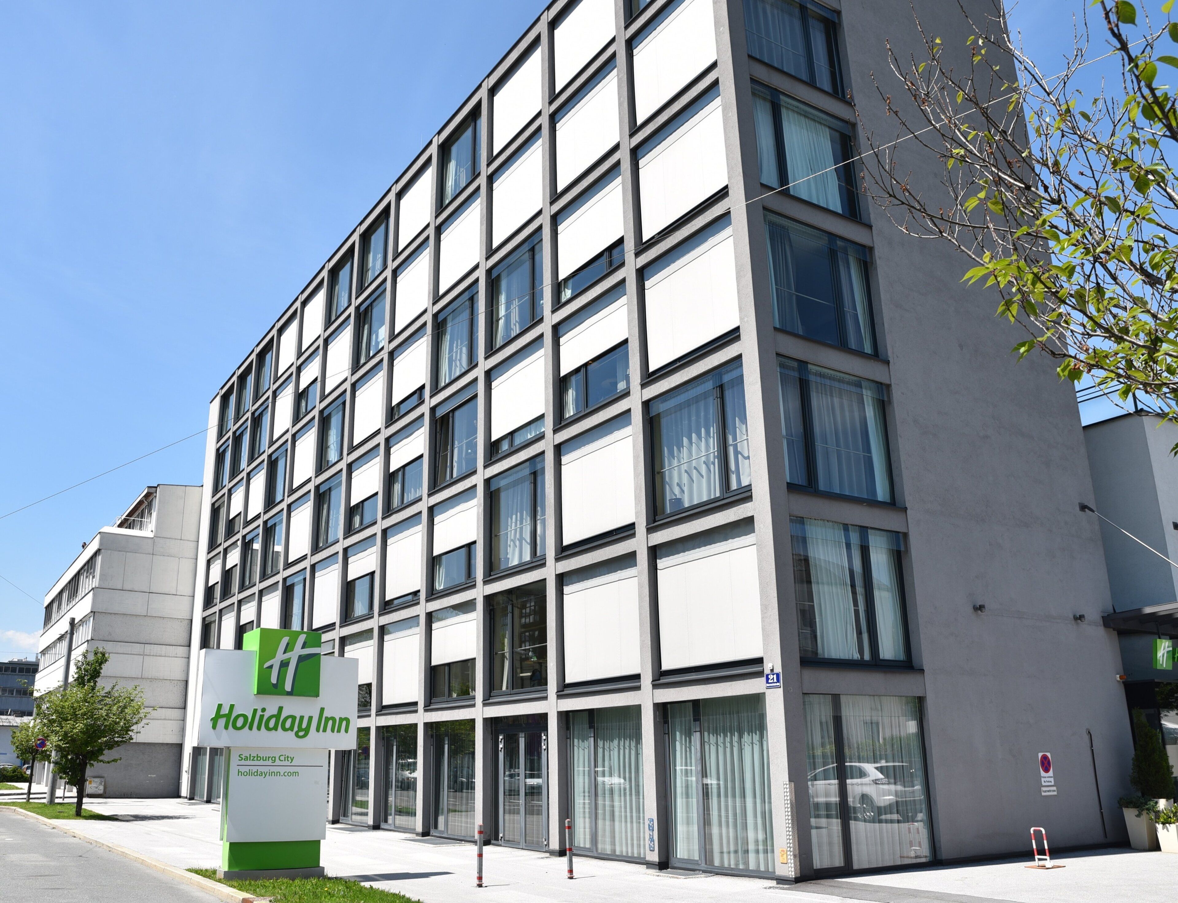 Een Holiday Inn gebouw met een modern ontwerp, herkenbaar aan een opvallend bord, grote ramen en een strakke gevel.