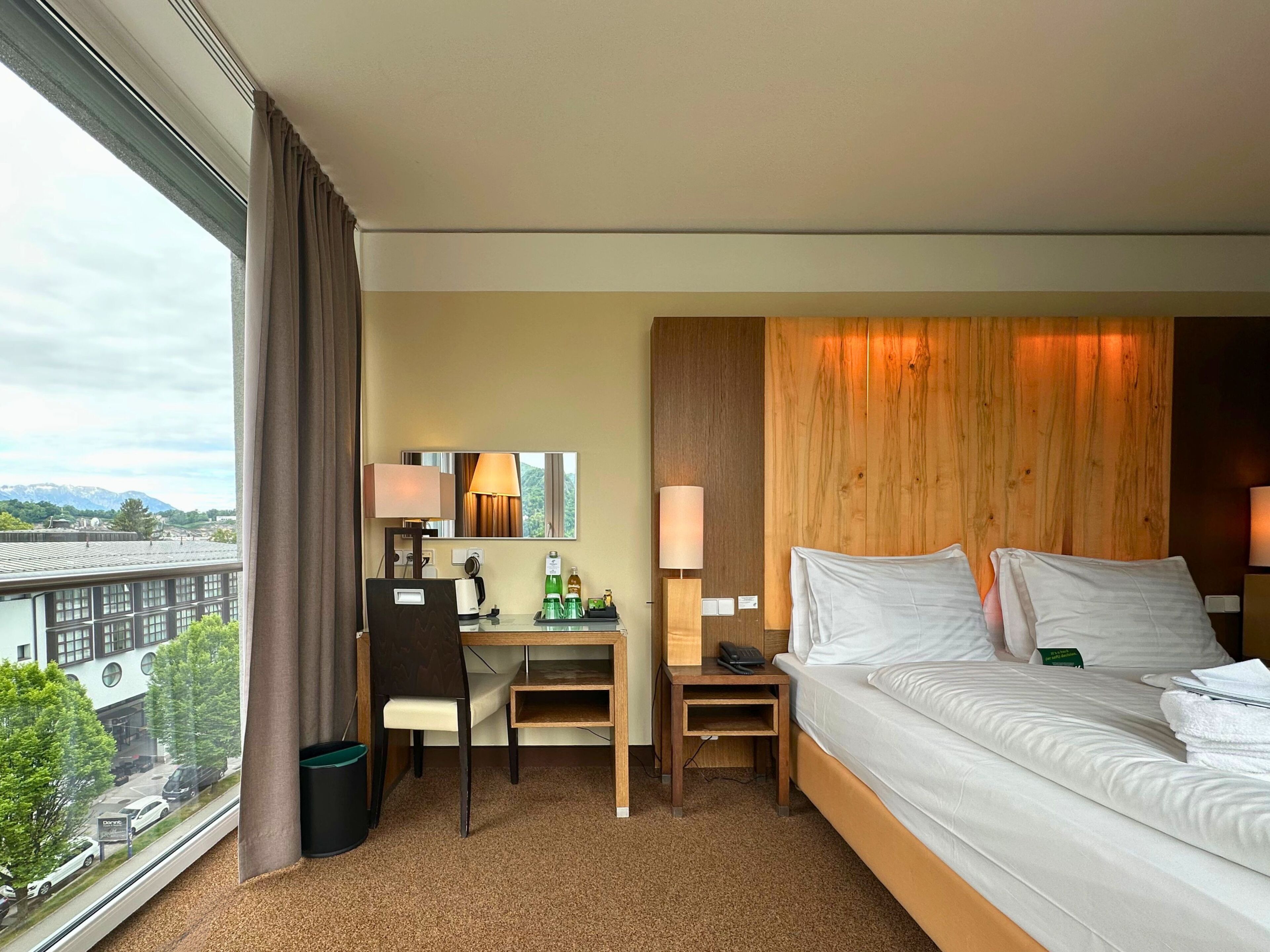 Una camera d'albergo con un letto, una scrivania, una sedia e vista sulla città.