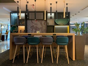 A modern bar area with a wooden counter, four bar stools, and pendant lighting. - Holiday Inn Salzburg City by IHG (Salzburg)