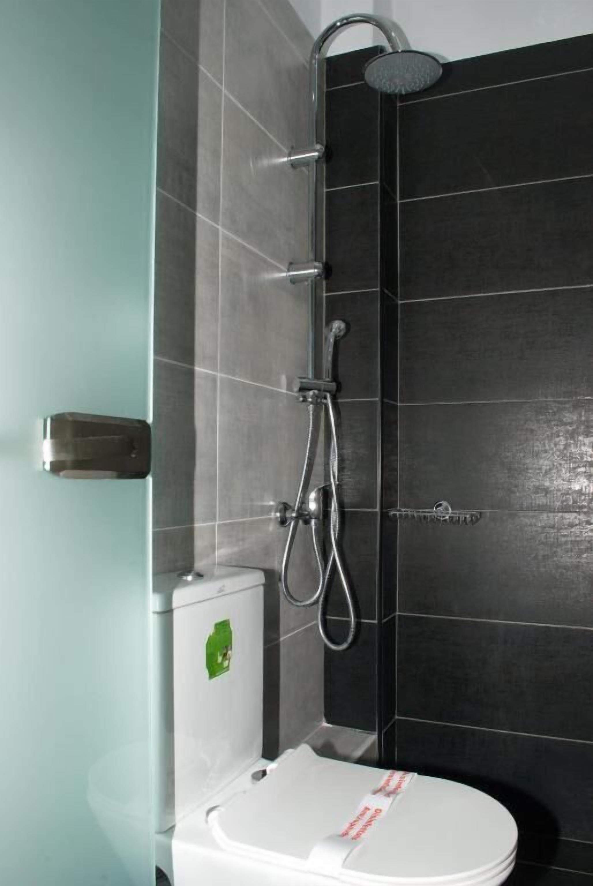 A bathroom with a toilet, a shower, and a sink.