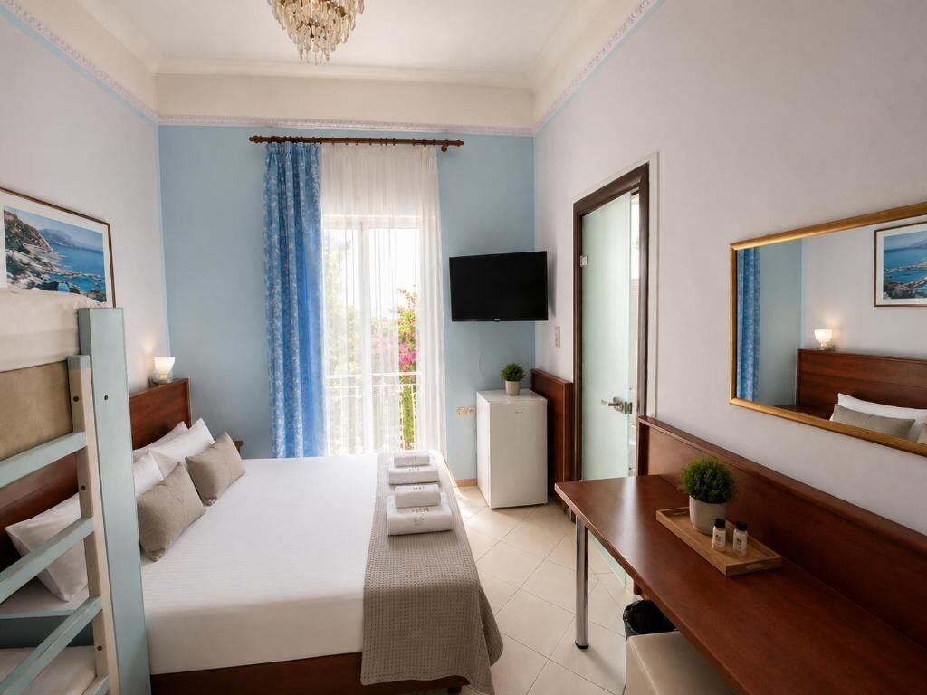 Ein Hotelzimmer mit Bett, Nachttisch, Fernseher und einem Fenster mit Vorhängen.