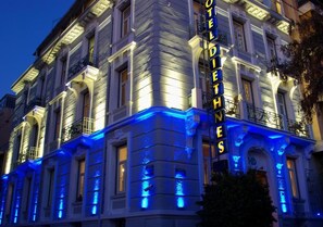 A hotel with a classic facade, illuminated signage, and a balcony. - Hotel Diethnes (Athens)