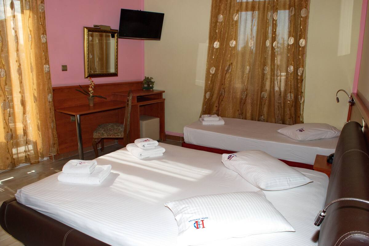 A hotel room with a bed, a desk, a chair, a television, and a bathroom.