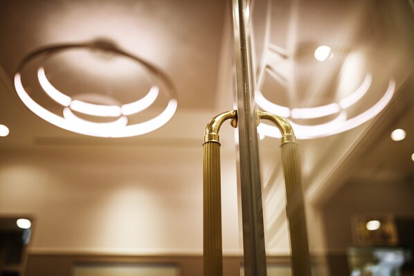 A close-up of a metallic, curved railing with a circular light fixture above it.
