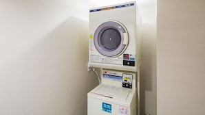 A stacked washer and dryer unit with control panels and labels. - JR East Hotel Mets Musashisakai (Musashino)