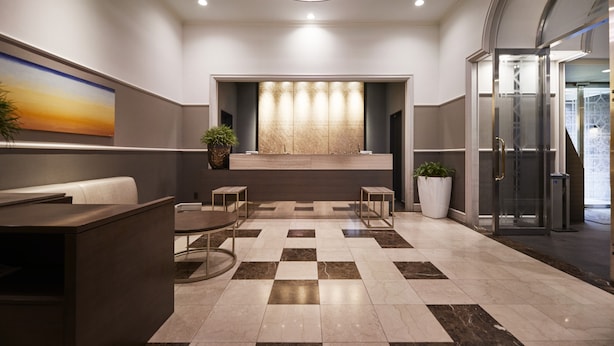 A modern lobby with a reception desk, seating area, and a glass elevator. - JR East Hotel Mets Musashisakai (Musashino)