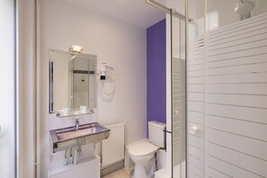 A bathroom with a white sink, a mirror, a hairdryer, a toilet, and a shower area.