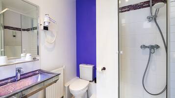 Une salle de bain avec une douche à parois de verre, des toilettes blanches et un meuble-lavabo avec un miroir.