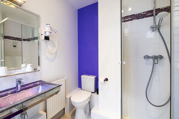 A bathroom with a glass shower enclosure, a white toilet, and a vanity with a mirror. - Hôtel Paris Legendre (Paris)