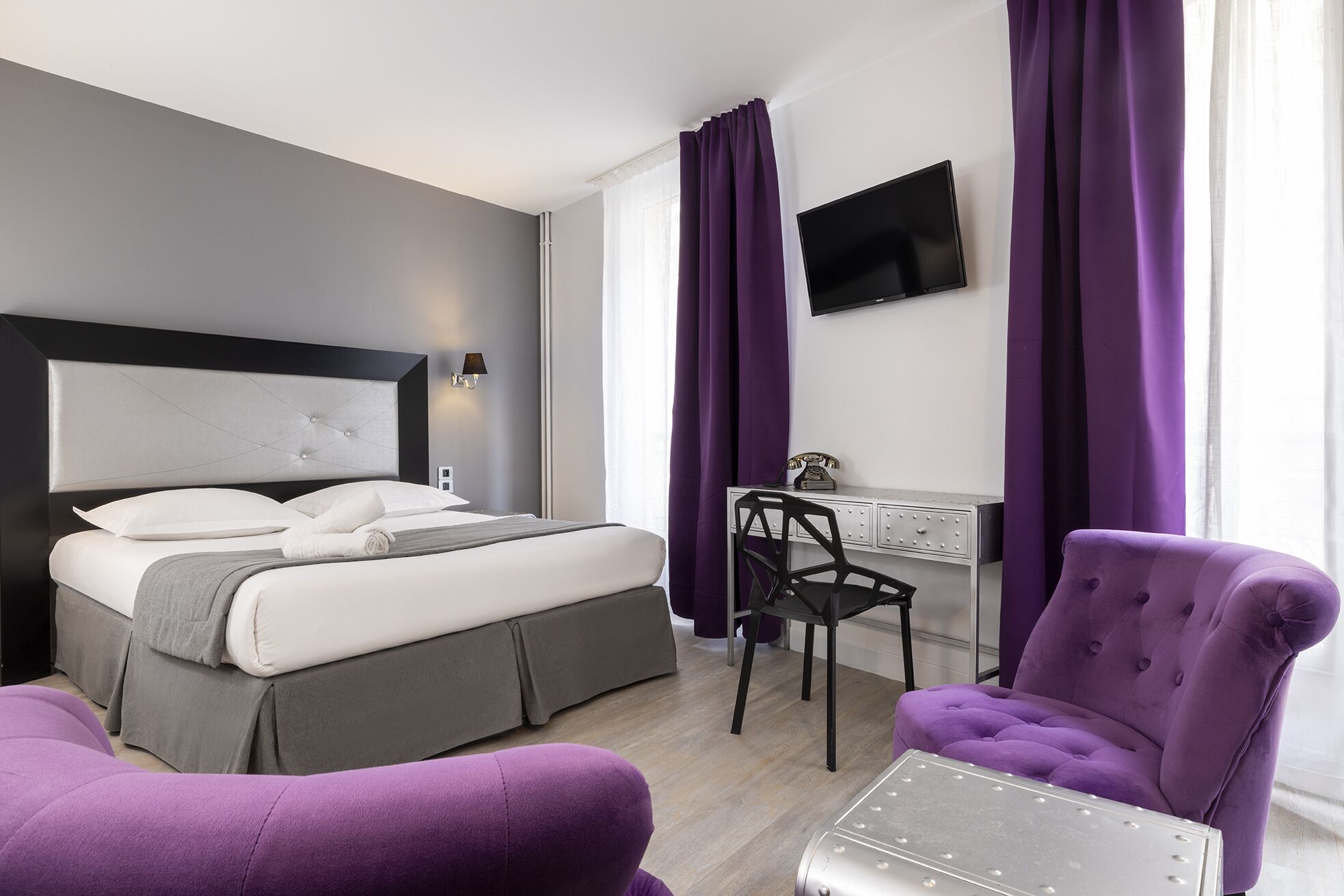 Une chambre d’hôtel moderne équipée d’un lit, d’un bureau, d’une chaise et d’un téléviseur.