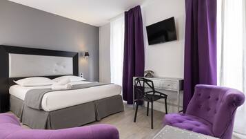 Une chambre d’hôtel moderne équipée d’un lit, d’un bureau, d’une chaise et d’un téléviseur.