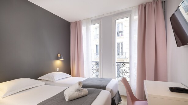 A hotel room with two beds, a desk, a chair, and a window with curtains. - Hôtel Paris Legendre (Paris)