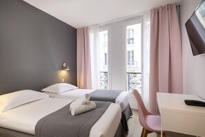 A hotel room with two beds, a desk, a chair, and a window with curtains. - Hôtel Paris Legendre (Paris)