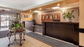A reception area with a reception desk, a potted plant, and framed artwork on the wall. - Best Western Rocky Mountain House Inn & Suites (Rocky Mountain House)