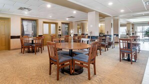 A spacious dining area with multiple round tables and wooden chairs, featuring a carpeted floor and recessed ceiling lighting. - Best Western Rocky Mountain House Inn & Suites (Rocky Mountain House)
